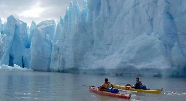 Dos viajeros navegan en kayak frente a glaciar en Torres del Paine