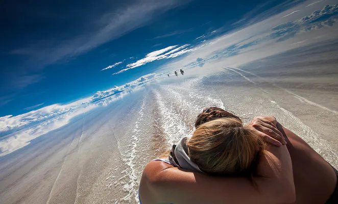 Dos viajeros sentados sobre el Salar de Uyuni inundado