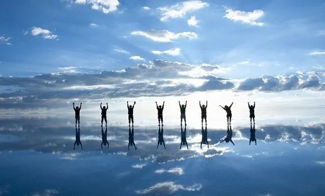 Viajeros se reflejan en el agua durante la mejor época para visitar el Salar de Uyuni