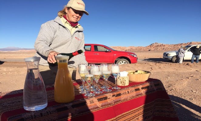 Mujer sirviendo champaña en el desierto de Atacama