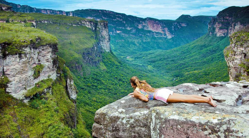 Mujer descansa sobre roca frente a paisaje