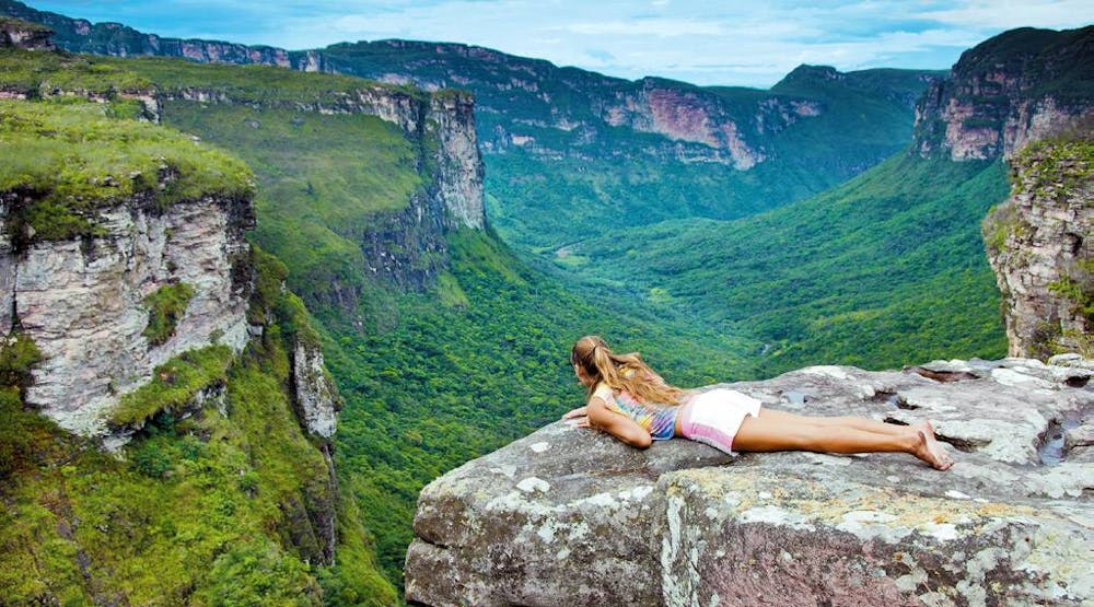 Mujer descansa sobre roca frente a paisaje