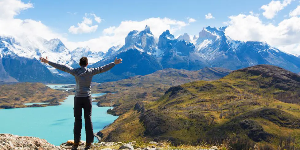 viajero extiende sus brazos mientras mira las montañas