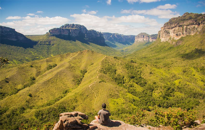 Hombre observa rutas y paisaje montañoso y verde