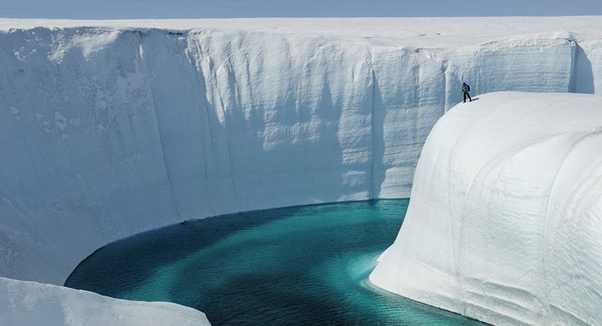 persona parada sobre el hielo de un glaciar