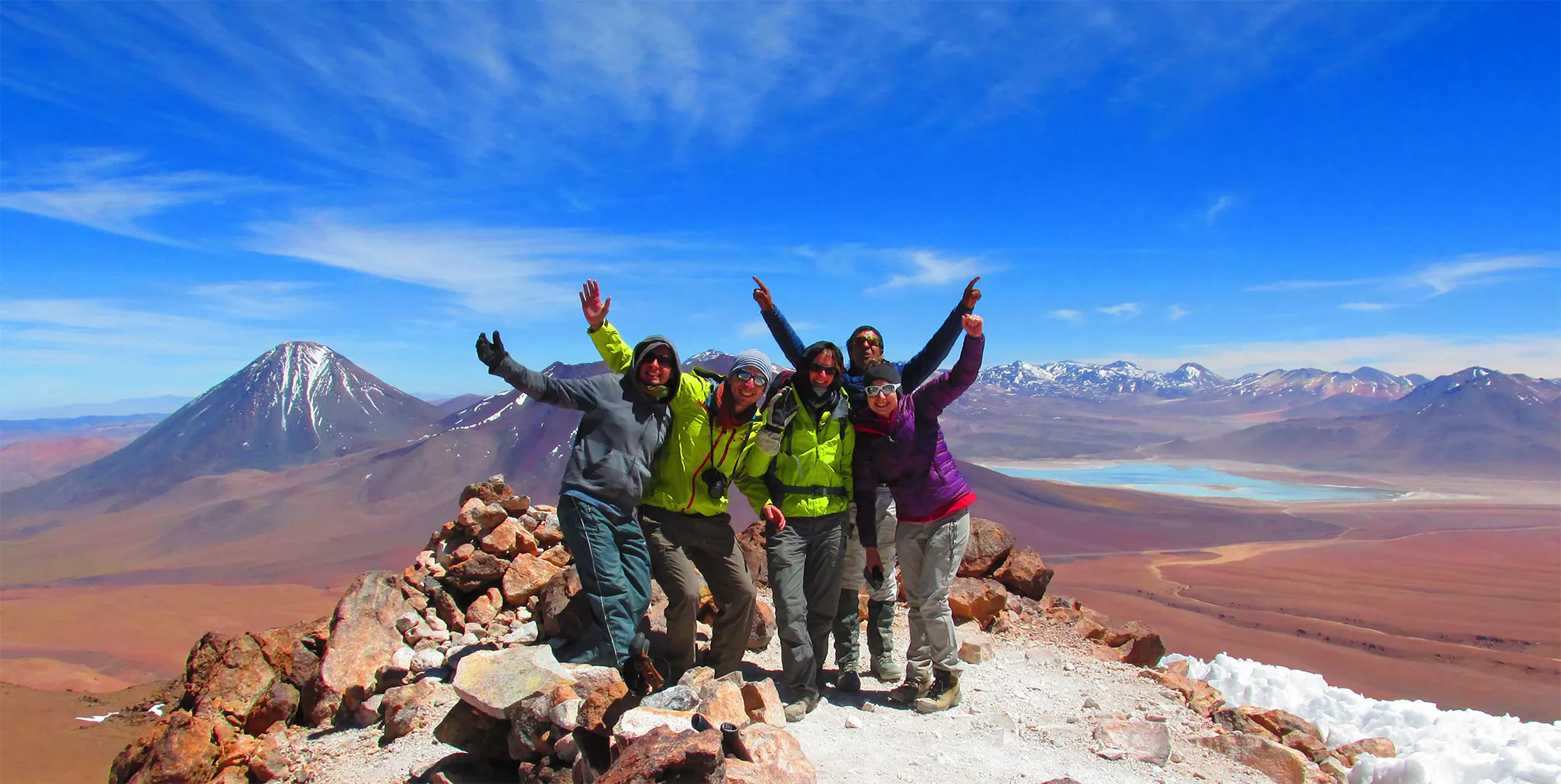 Viajeros en cima de volcan y otros volcanes al fondo del paisaje