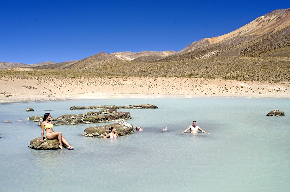 Personas bañandose en termas en el desierto