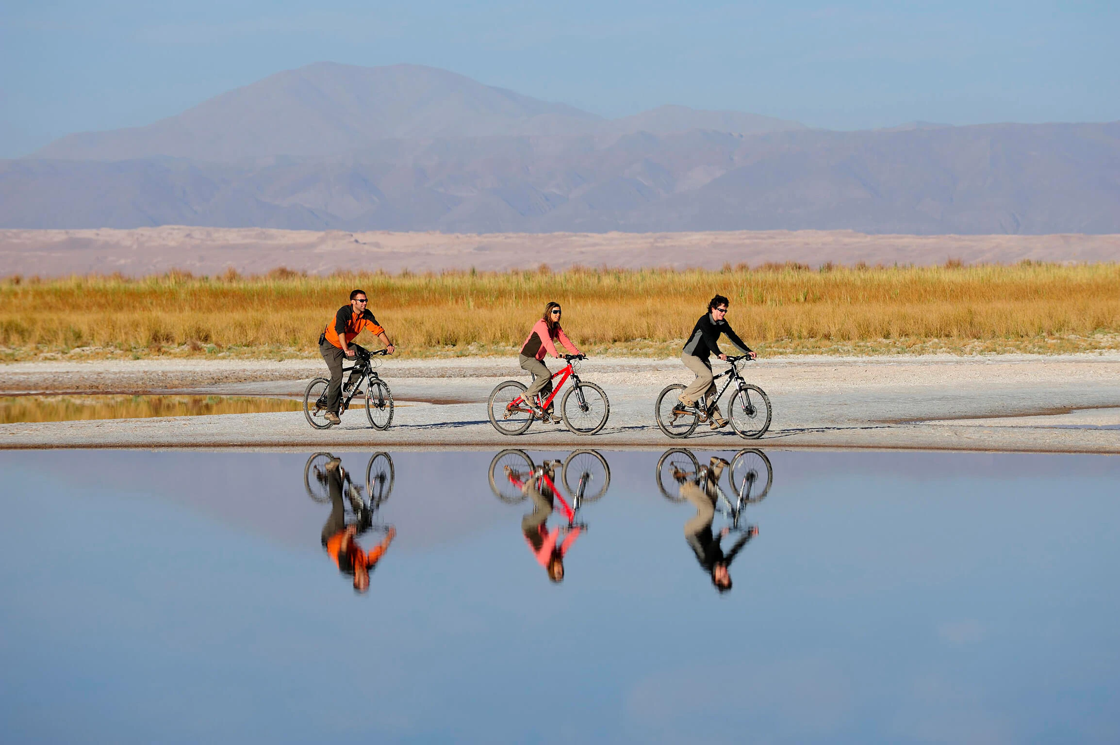 Tres ciclistas frente a una laguna