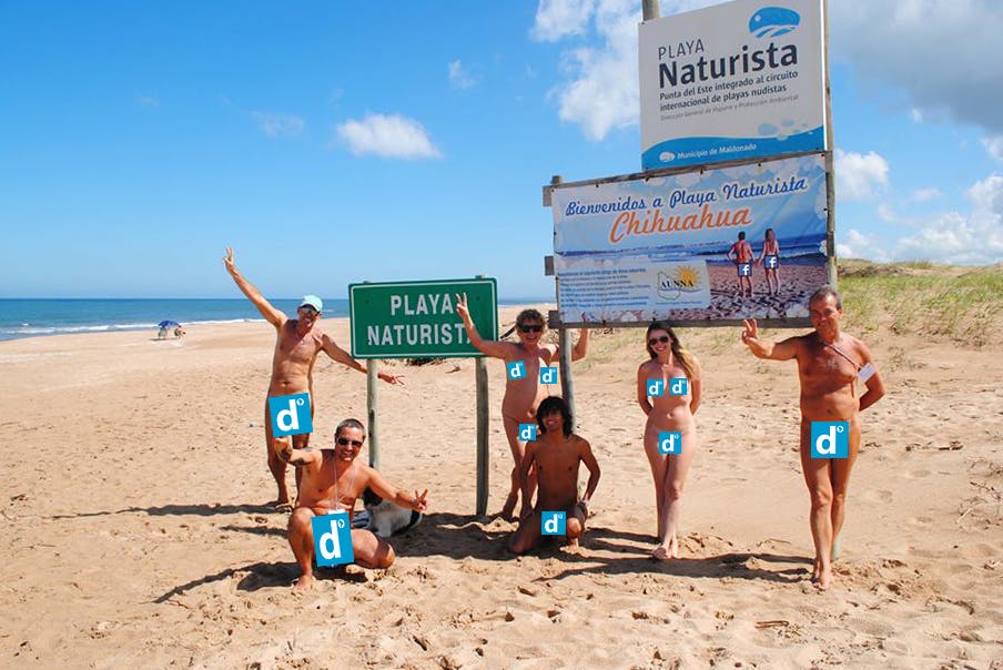 Nudistas en la playa posando para una foto