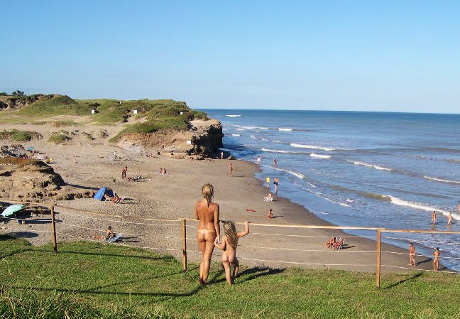 Madre e hija desnudas observan playa