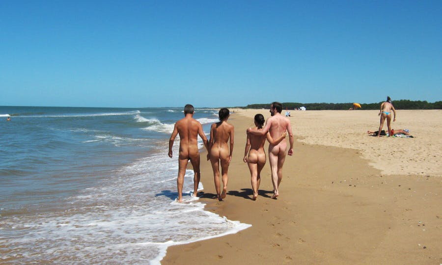 Nudistas caminando por la playa