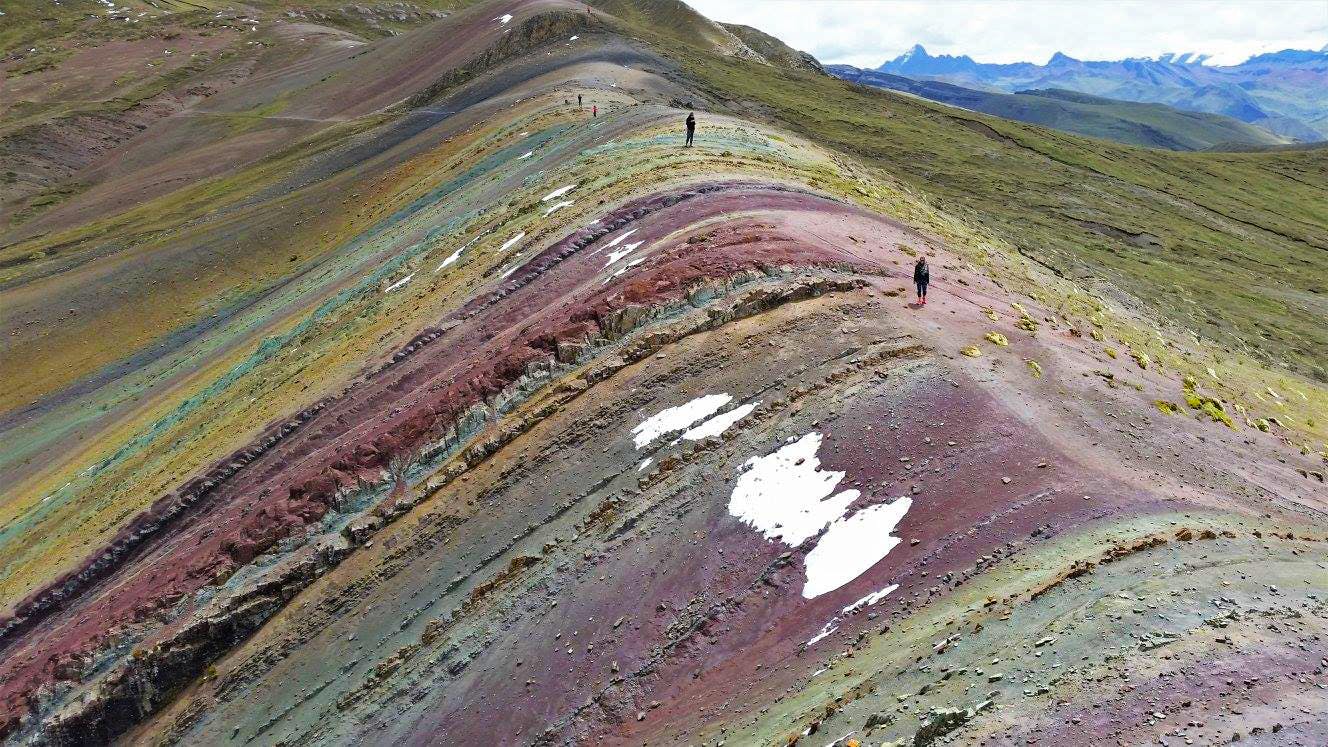 Viajeros caminando por montaña de colores Palcoyo