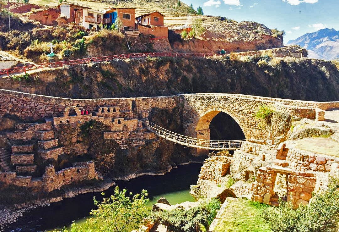 Puente colgante y de piedra frente a casas