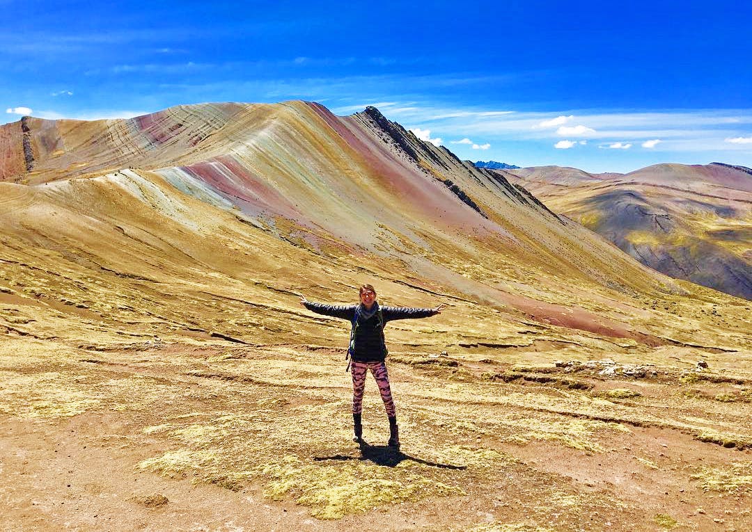 Viajera extendida de brazos frente a cerros de colores