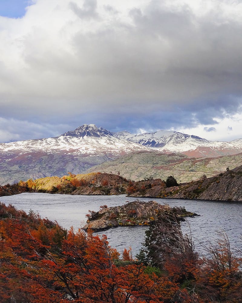 Lago, montañas, nubes y arboles rojos