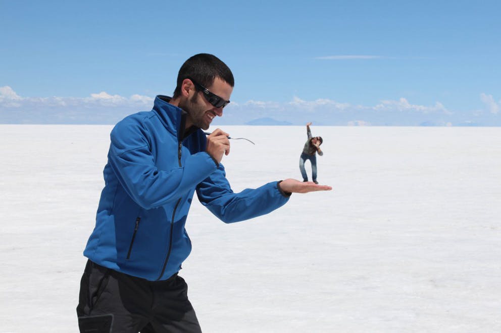 Dos viajeros jugando con efectos de perspectiva en el Salar de Uyuni