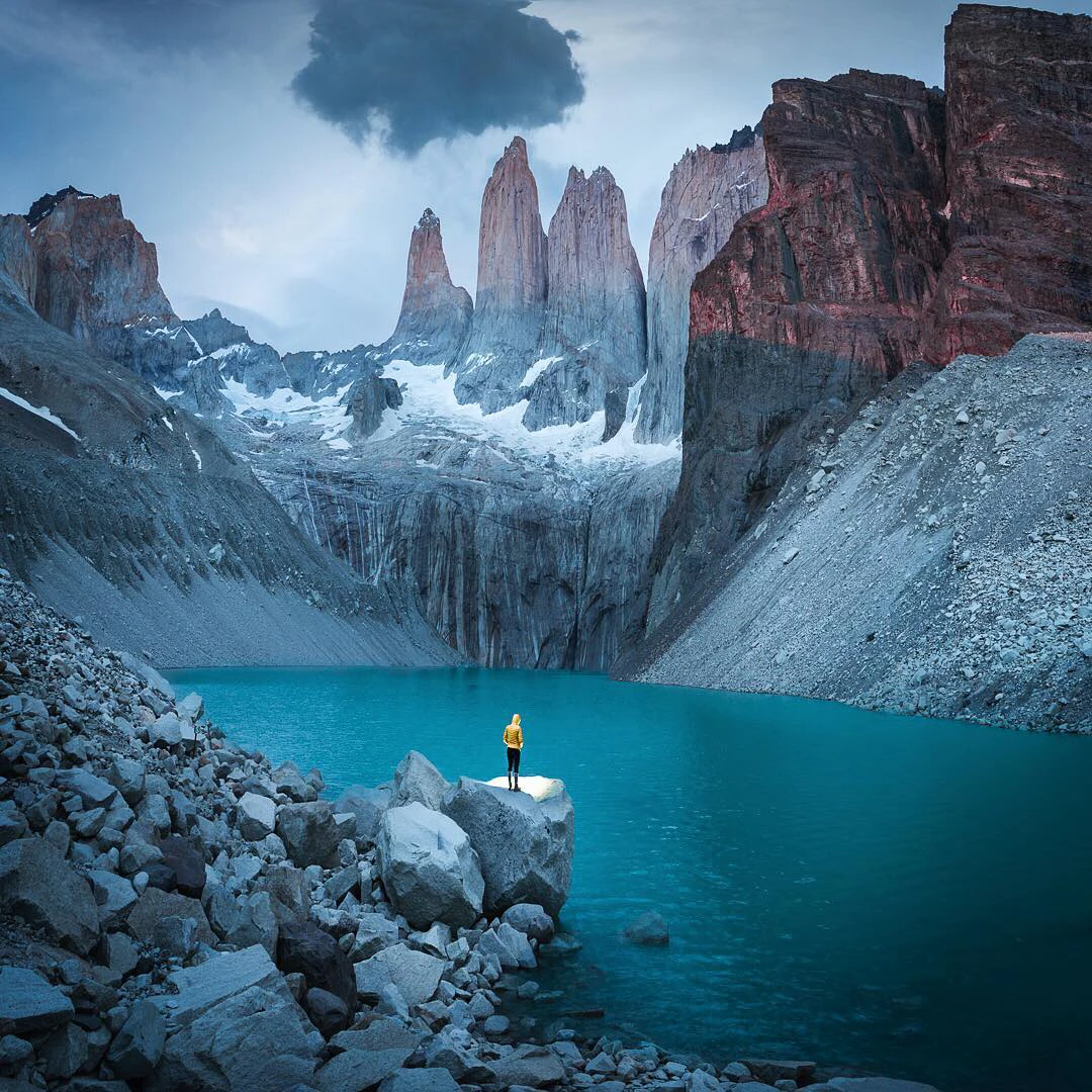 Viajero frente a la laguna y paisaje montañoso en Torres del paine