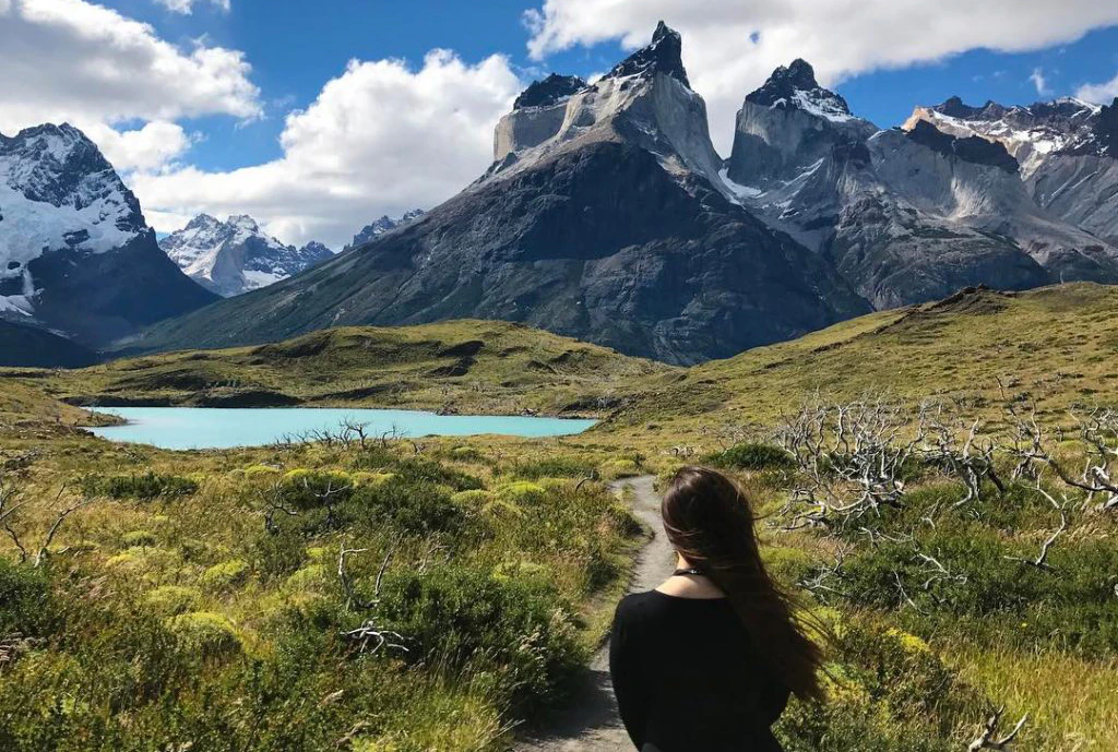 Viajera observando laguna color calipso y paisaje montañoso de fondo en Torres del Paine