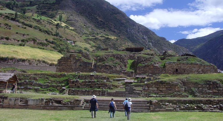 Tres viajeros caminando hacia restos arqueológicos