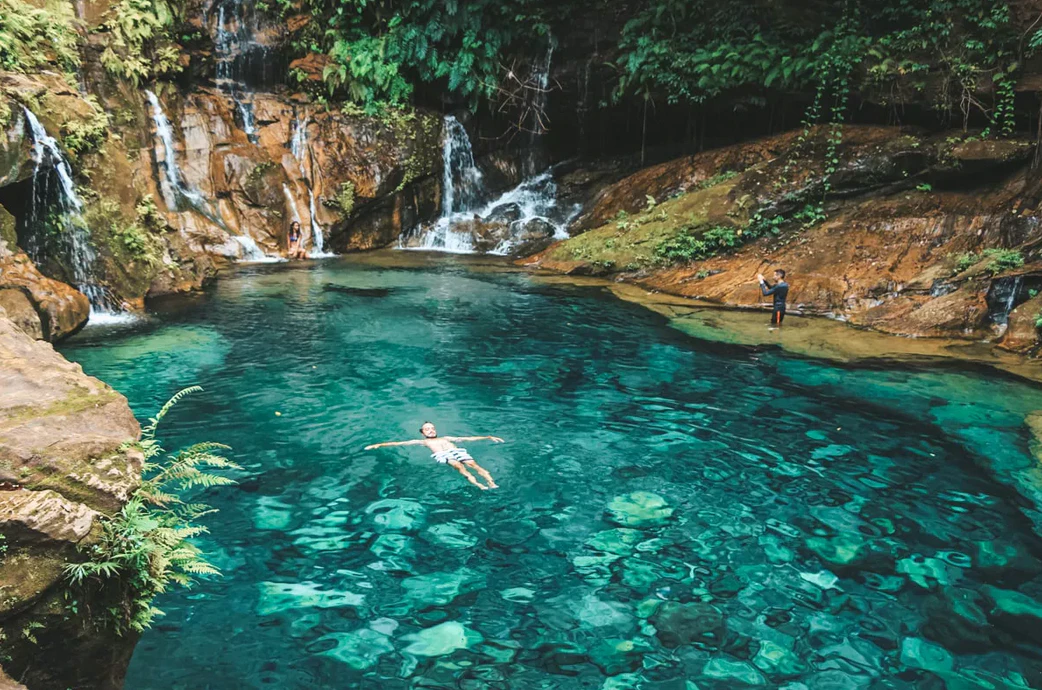 Viajante tomando banho em uma piscina natural
