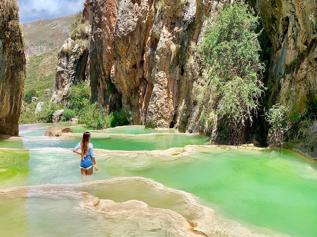 Chica sobre piscinas naturales de color esmeralda en Ayacucho