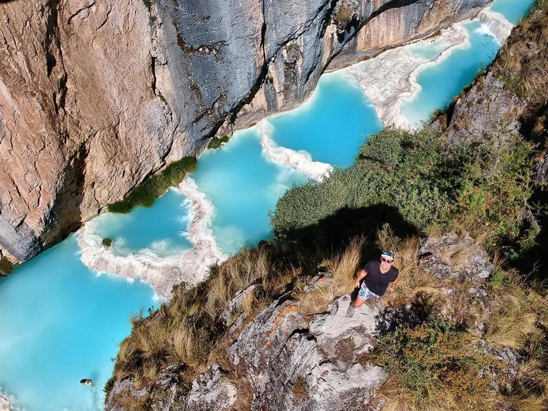 Joven en un mirador observando aguas turquesas de Ayacucho