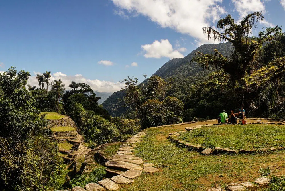 Grupo de viajeros descansa frente a ruinas arqueológicas de la Ciudad Perdida