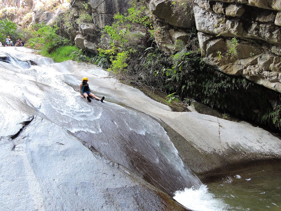 Viajera delsizandose por tobogan en rocas