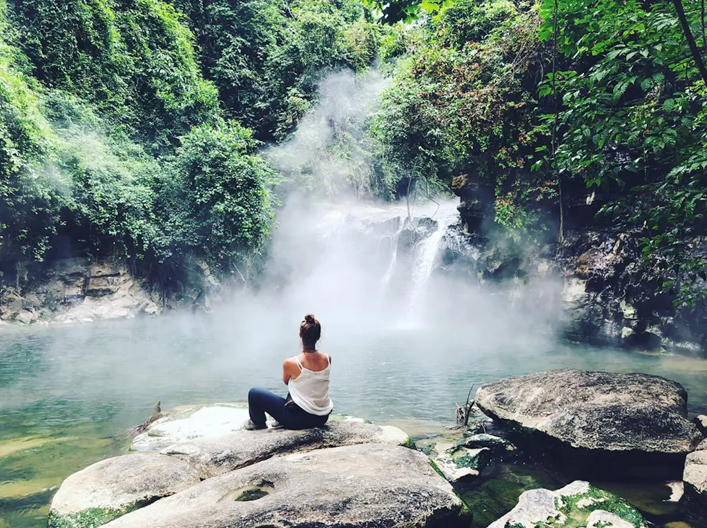 viajera-mayantuyacu Viajera sentada frente a pequeña caída de agua de río hirviente
