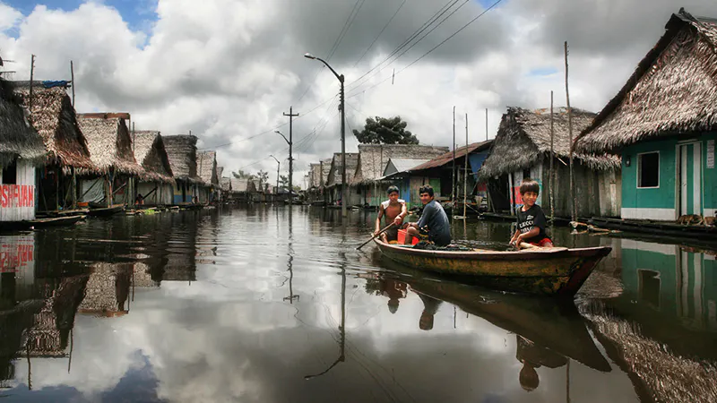 Grupo de locales navegando en bote por casas flotantes