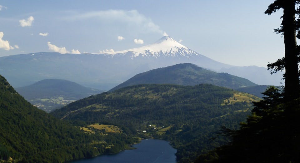 Volcán humeante frente a laguna