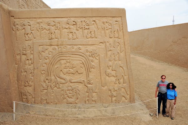 Dos viajeros junto a complejo arqueológico en Perú