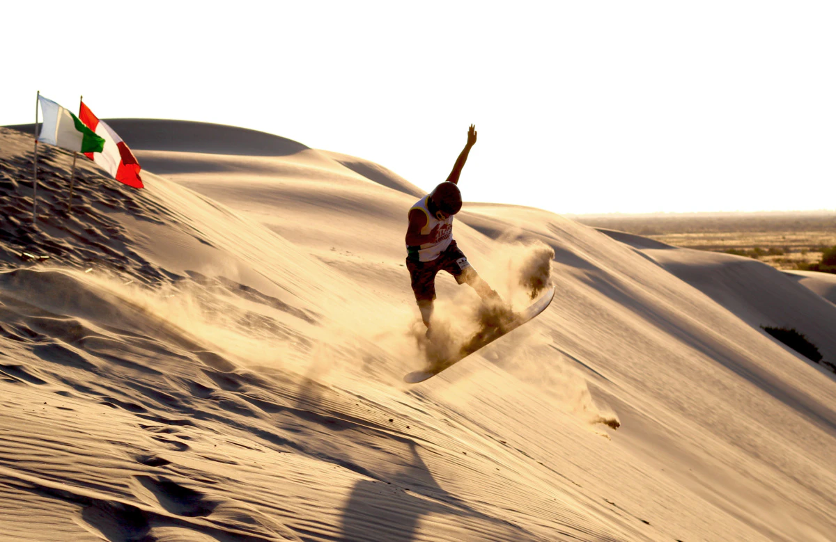 Hombre haciendo sandboard en dunas de piura