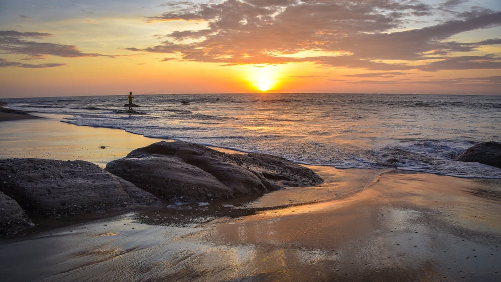 Playa con un pescador en el atardecer