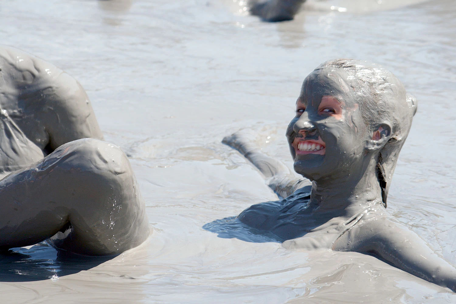Mujer sonríe en una poza de barro