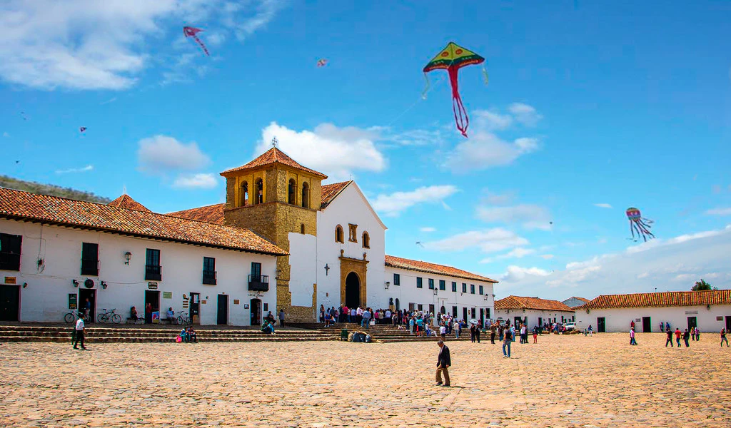 Iglesia y plaza con niños jugando con volantines en uno de los bellos lugares en colombia