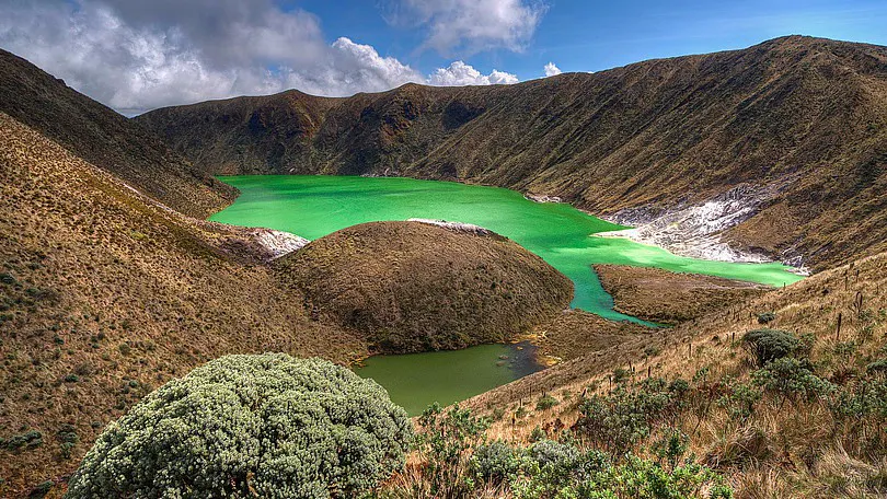 laguna color verde esmeralda enmedio de montañas