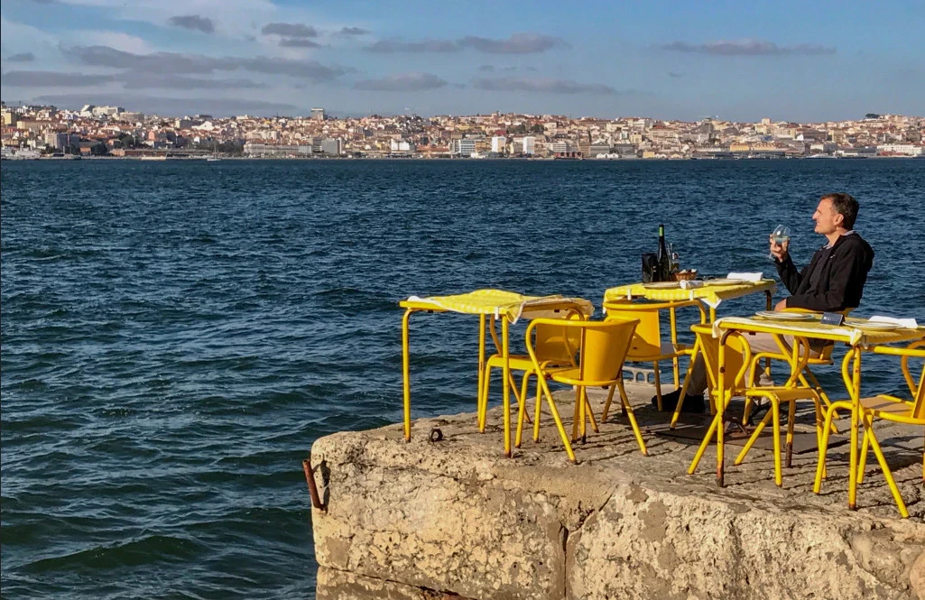 Hombre sentado en una mesa amarilla mirando la ciudad