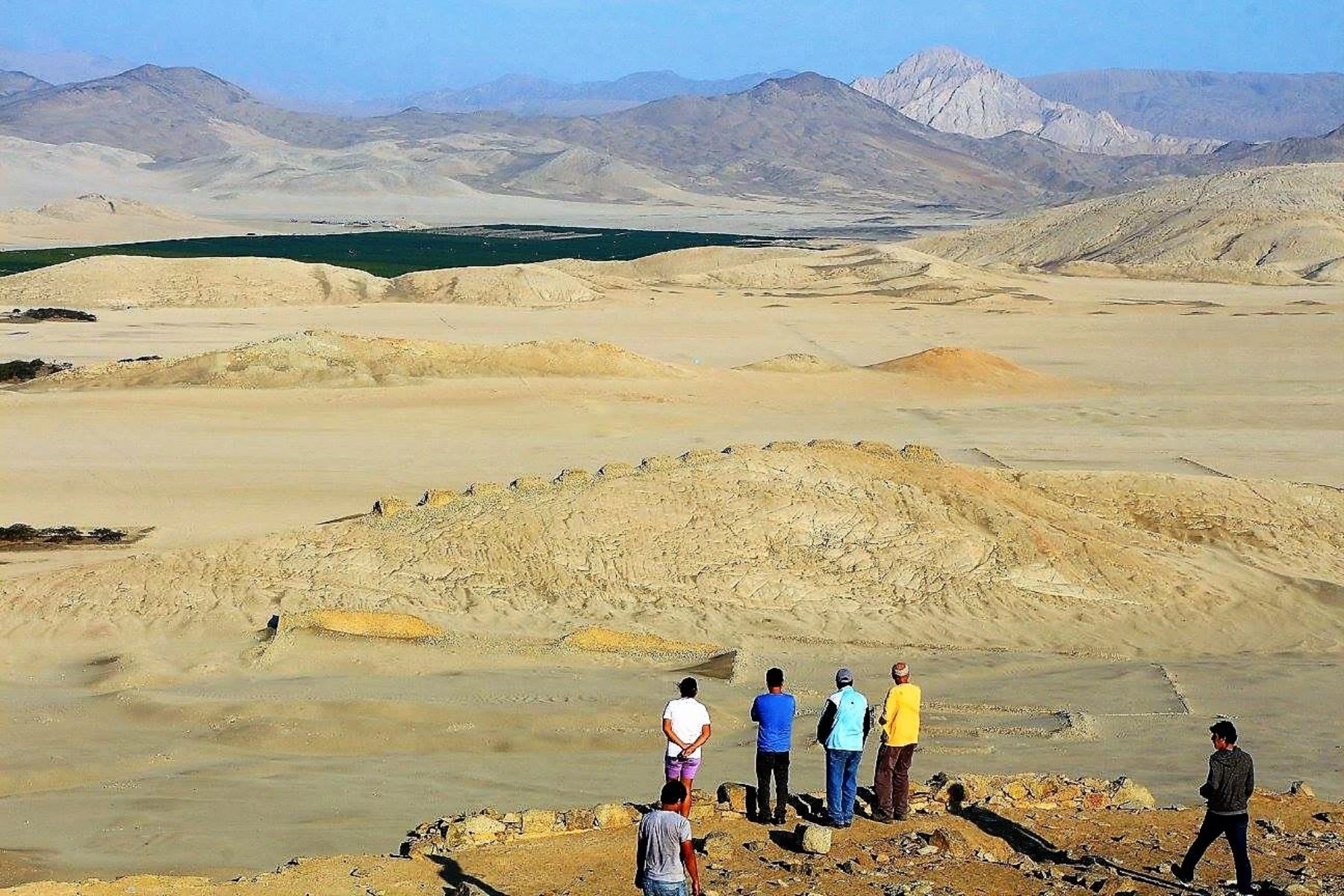 Personas observando restos arqueológicos en el desierto