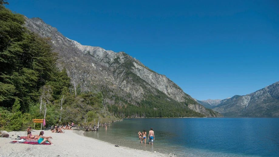 Personas bañandose en la playa de lago en Bariloche