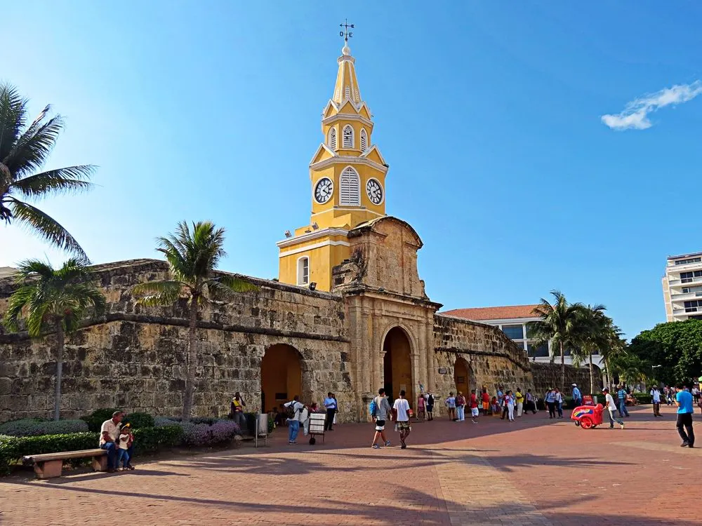 Personas caminando frente a torre del reloj en cartagena