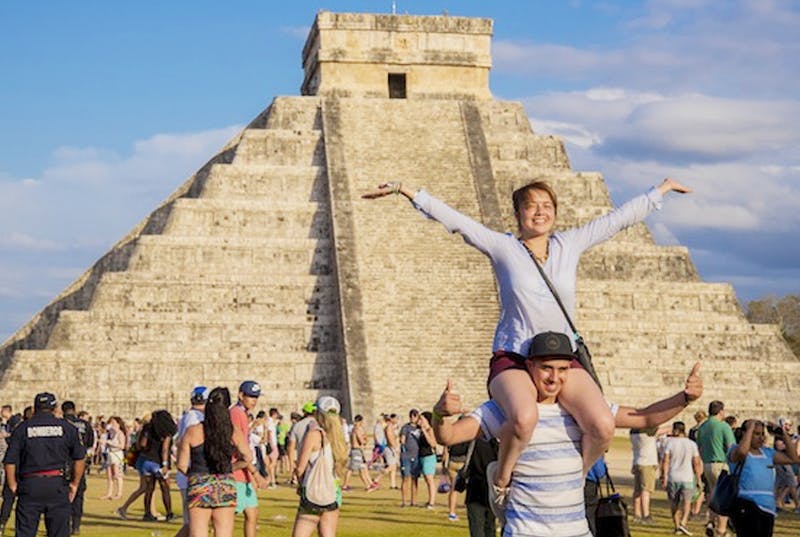 Dos turistas posan frente a pirámides de chichen itzá