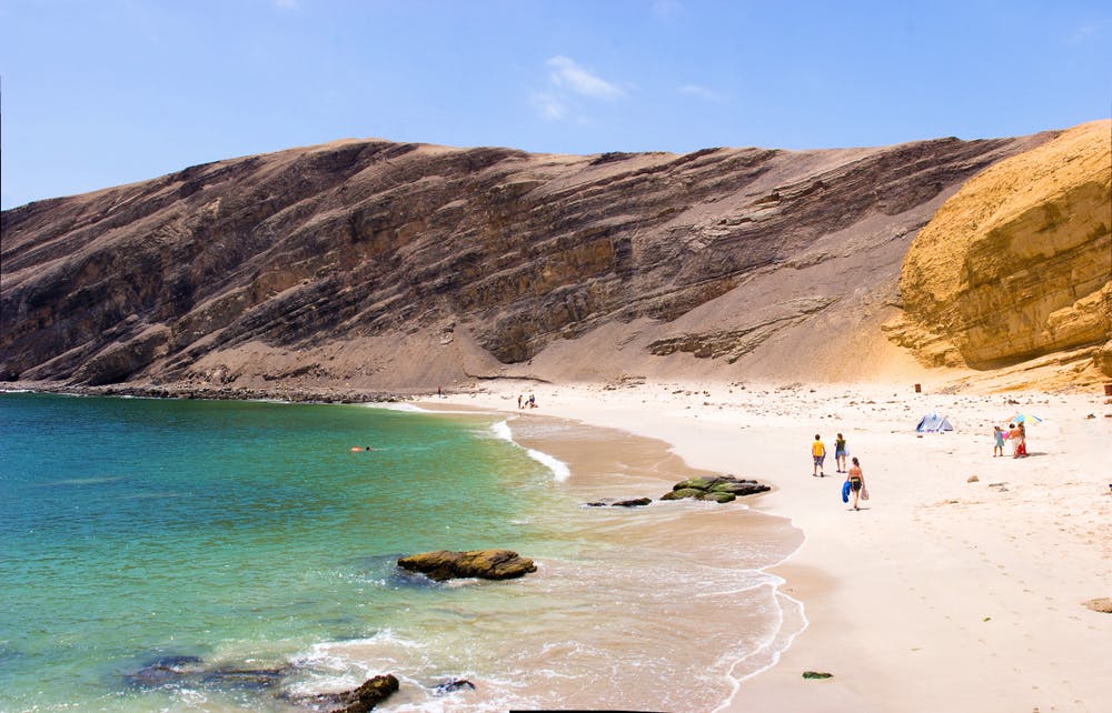 Personas caminando por una playa en uno de los lugares turísticos del Perú