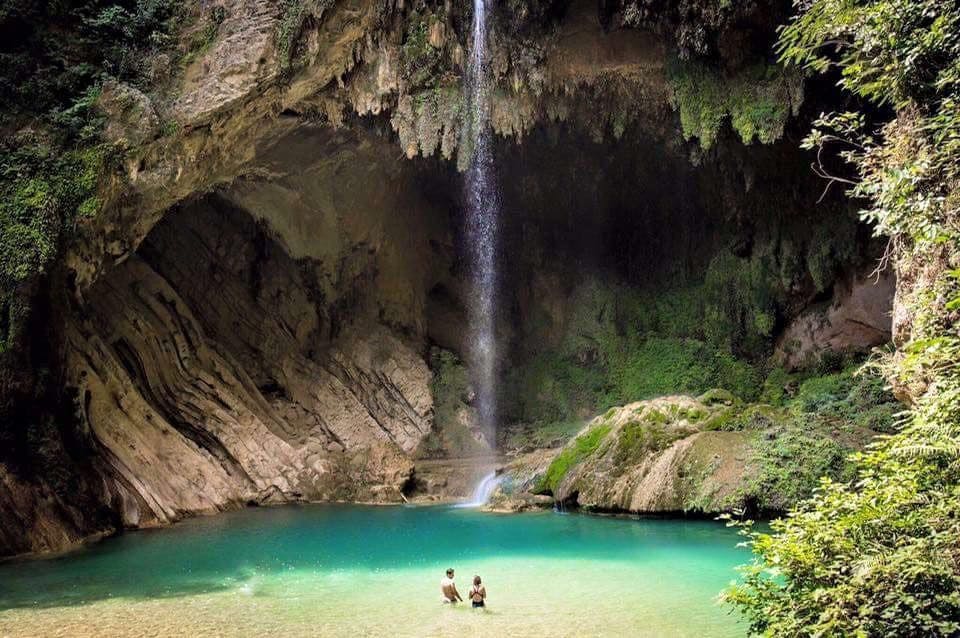 Dos personas observando cascada en una cueva en méxico