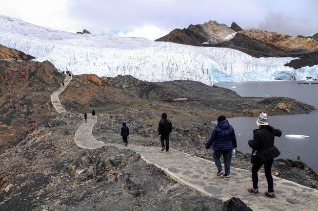 Personas caminando hacia glaciar en lugares turísticos de Huaraz