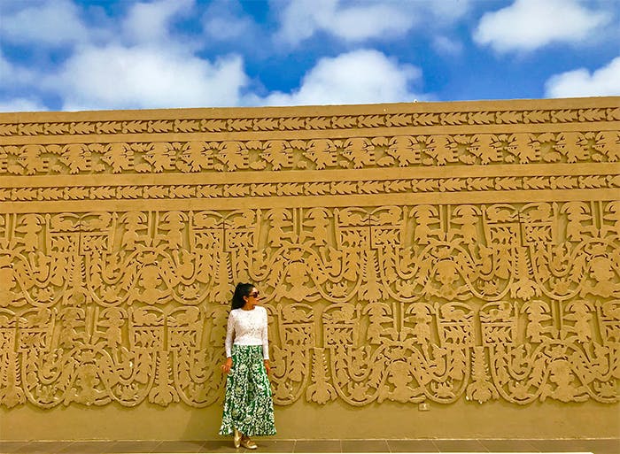 Mujer frente a muro de centro arqueológico en Trujillo