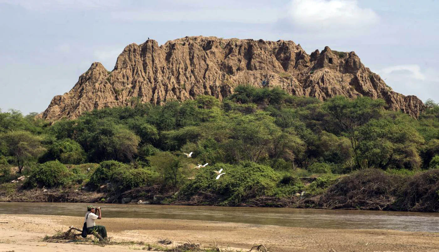 Persona observando paisaje frente a gran pirámide de barro