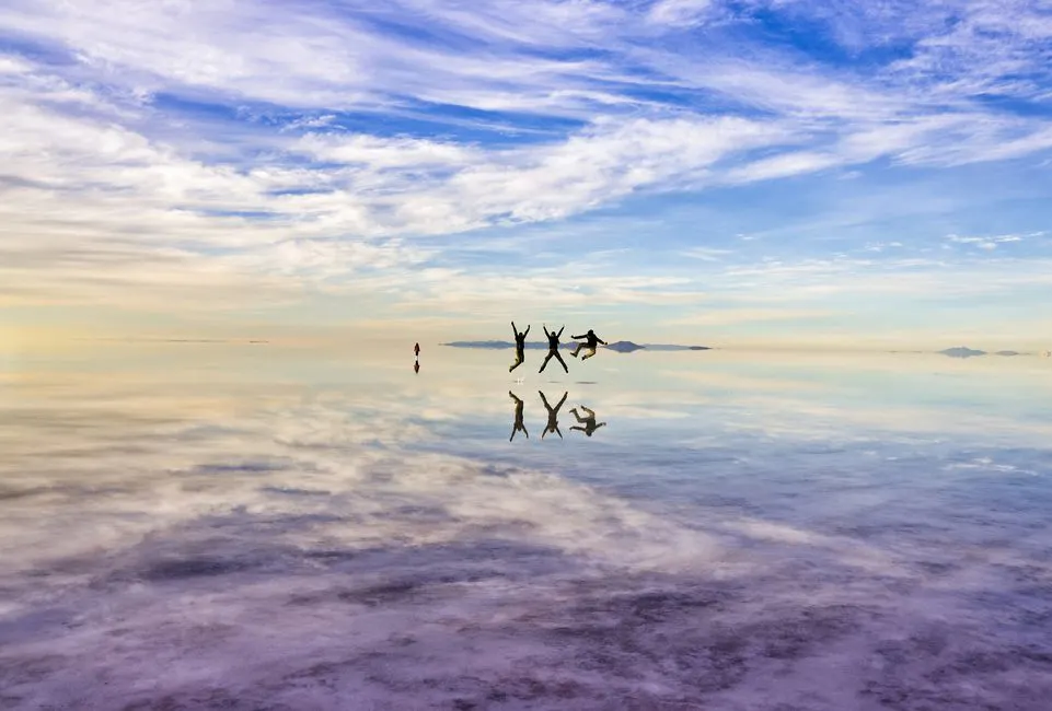 Viajeros en medio de salar de uyuni durante efecto espejo